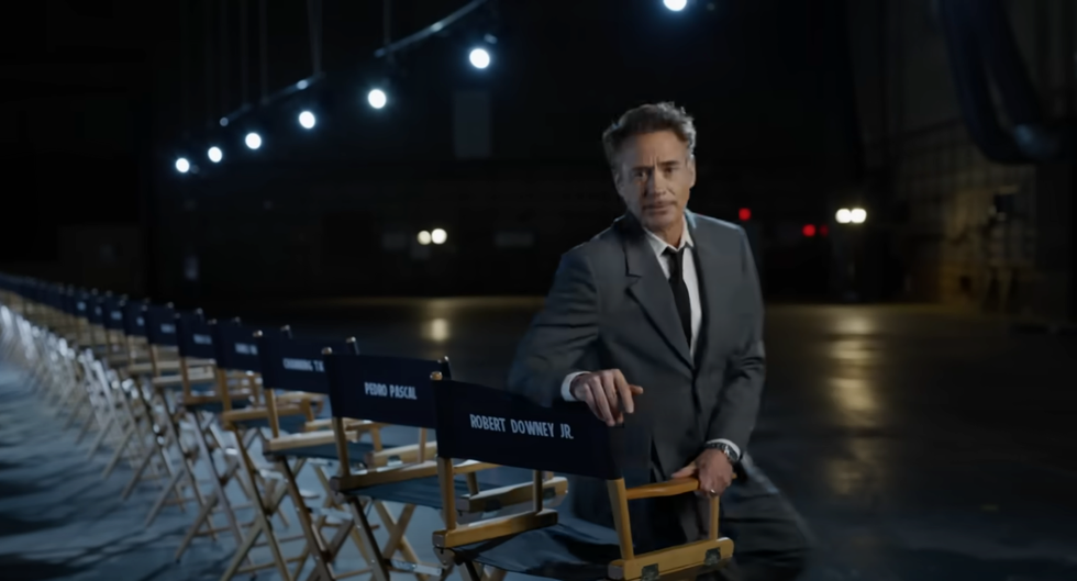 robert downey jr sits at the end of a row of director's chairs with names of all the actors who are going to be in avengers doomsday