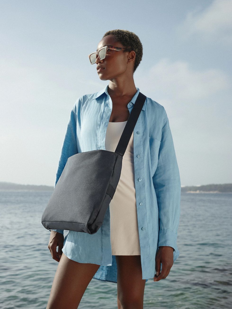 a model carries an away messenger bag in a roundup of away luggage outdoor launch 2022