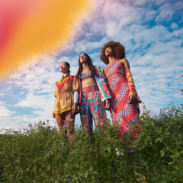 a group of women in colorful dresses standing in a field