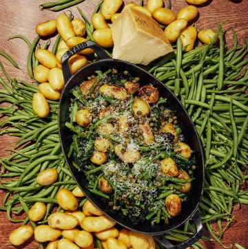 Farmer J recipe: Parmesan Baby Potatoes + Green Beans a dish with baby potatoes and green beans on a table scattered with more baby potatoes and green beans.
