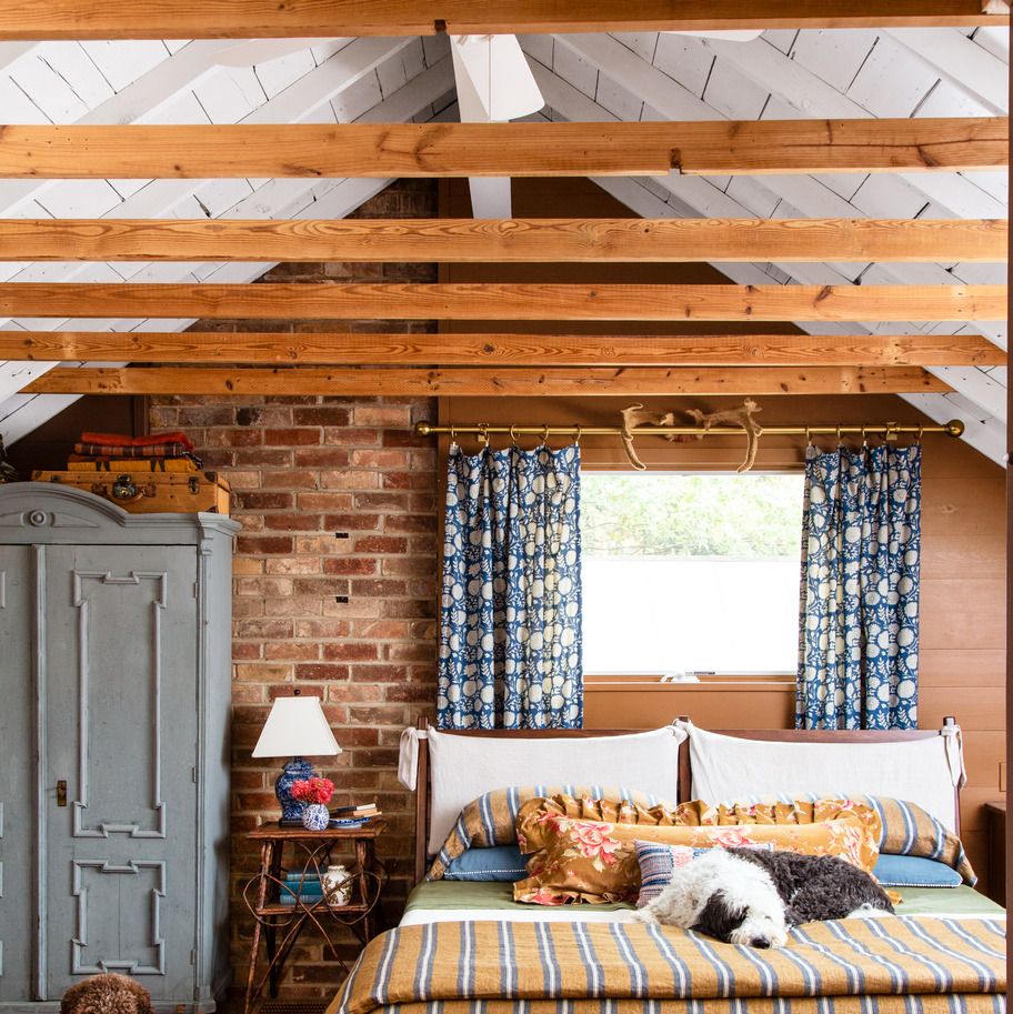 a bedroom in a mountain house that has stripes and florals and brick and a vintage rug