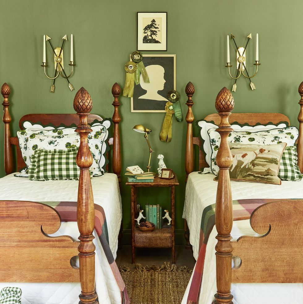 a small bedroom with earthy mossy green walls and two twin beds that are made up in green and white linens