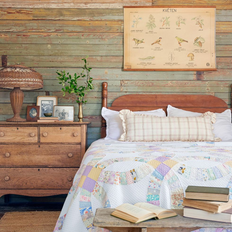 the wall behind the bed is covered in wood salvaged from other parts of a rescued house and the bed is covered with a double wedding ring quilt