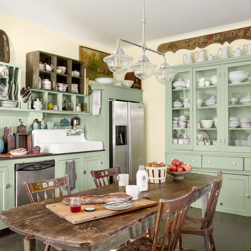 a farmhouse kitchen with mint green cabinets and a wood table in the middle