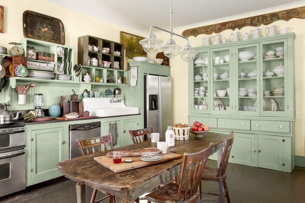 a farmhouse kitchen with mint green cabinets and a wood table in the middle