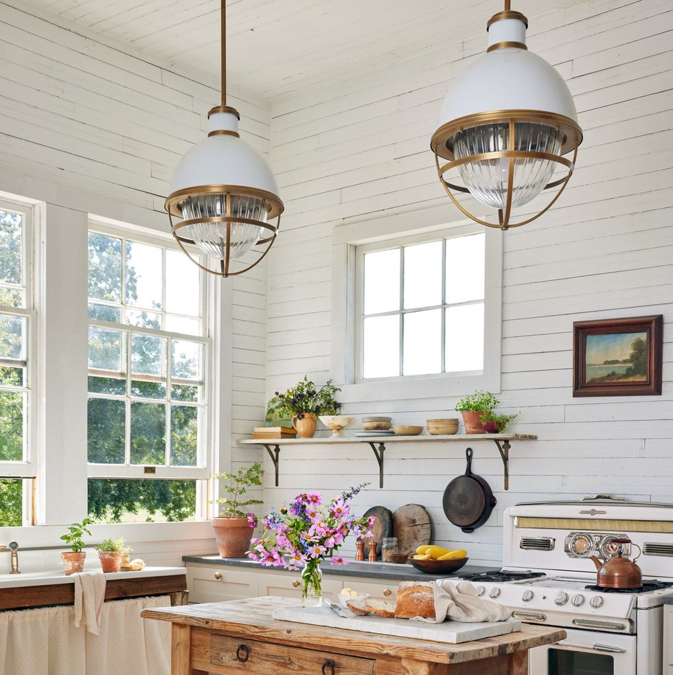 a tiny farmhouse kitchen packed with charm like a skirted sink and open shelving and a pine island and a vintage stove