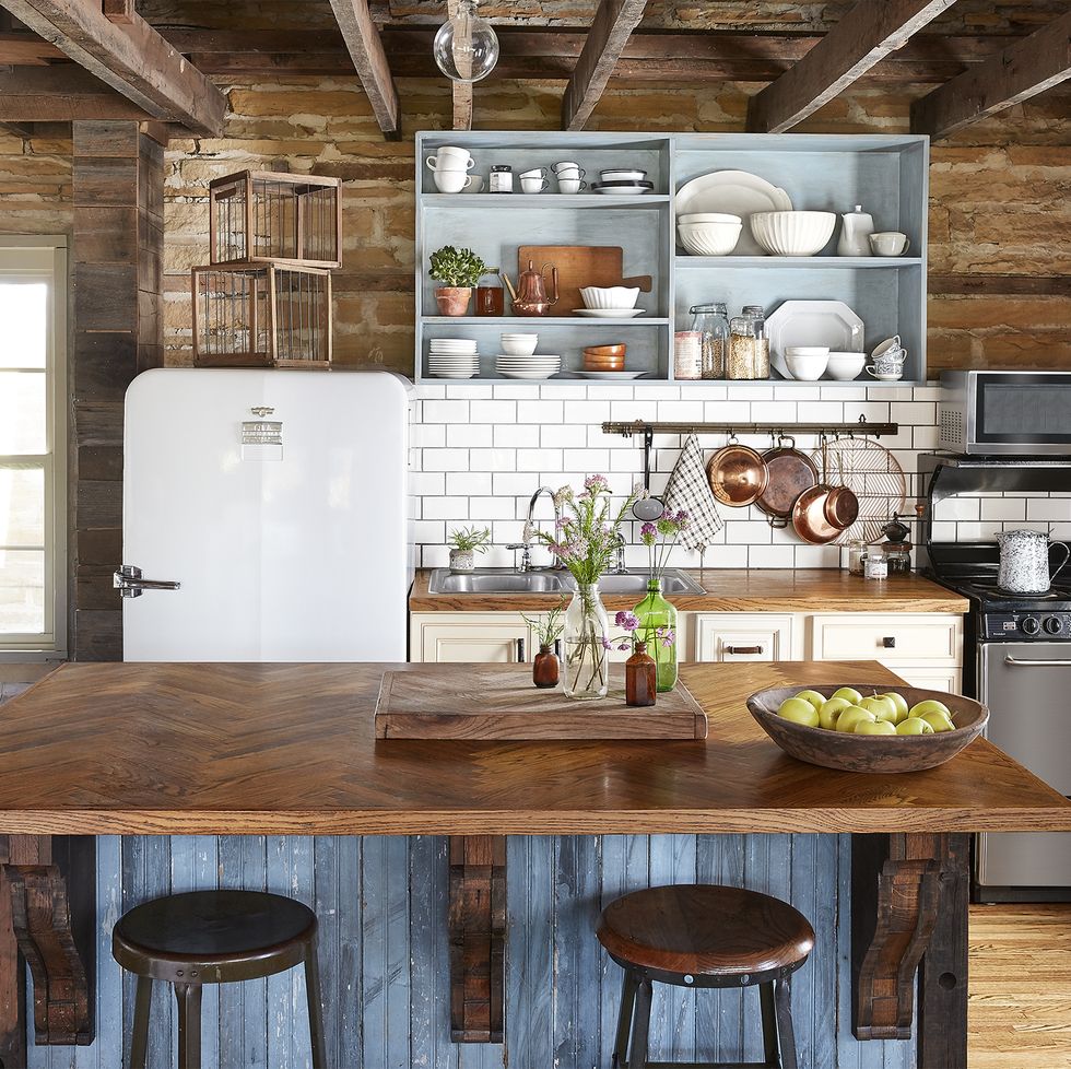 a farmhouse kitchen that has bare walls and reclaimed blue washed wood makes up the kitchen island