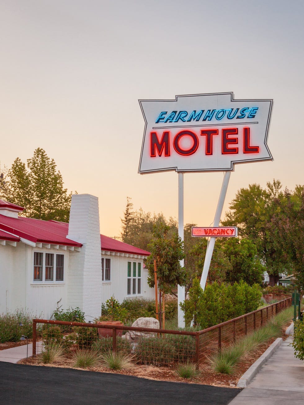 sign for farmhouse motel with surrounding landscaping and pathway