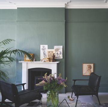 a room painted in green and yellow farrow ball paint with fireplace and armchairs