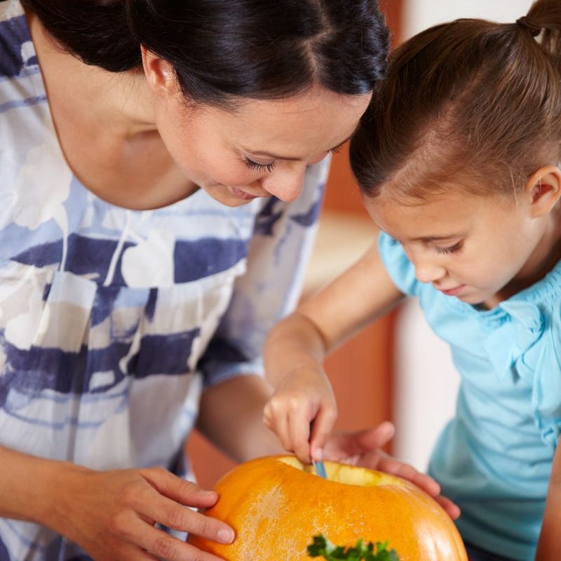 halloween trivia mom and daughter carving a pumpkin