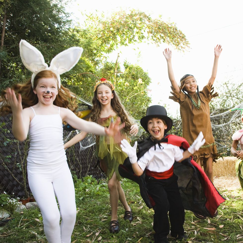halloween trivia kids dressed up in halloween costumes jumping in backyard