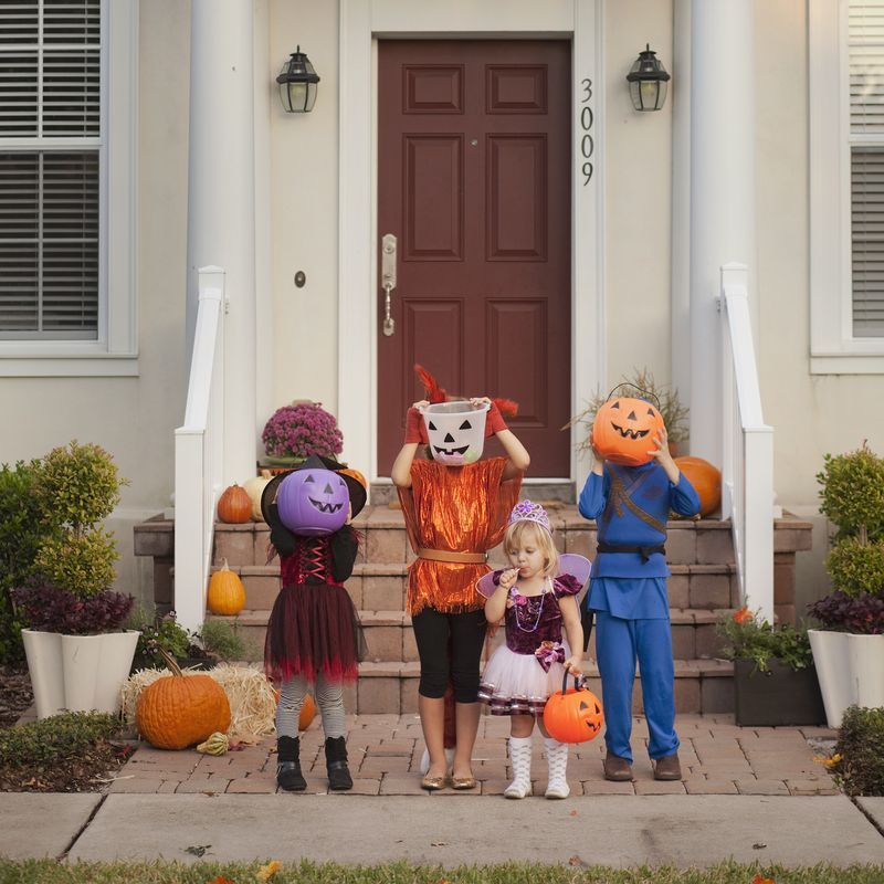halloween trivia kids dressed up in costumes standing outside their door