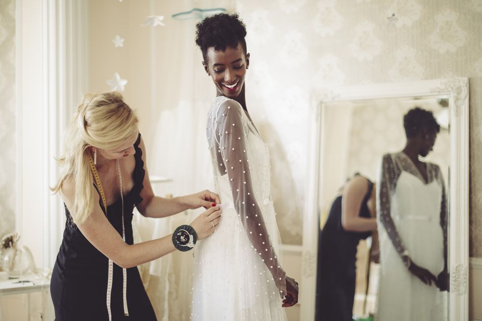 fashion designer is adjusting the wedding dress