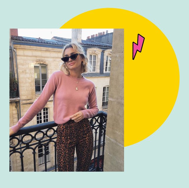 french fashion icon anne laure mais stands on a balcony in paris wearing a pink jumper, leopard trousers and black sunglasses