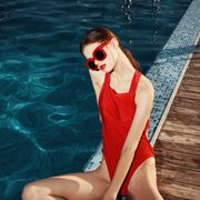 fashion woman in the pool in a red swimsuit and stylish glasses