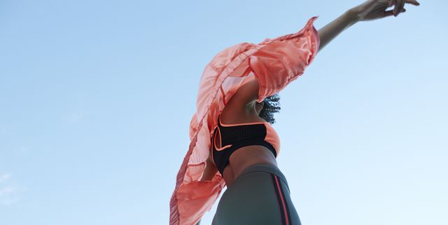 Fashionable woman wearing jacket with sports clothing against clear sky