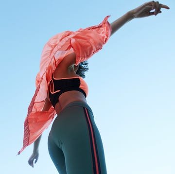 Fashionable woman wearing jacket with sports clothing against clear sky