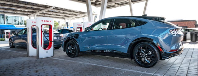 ford mustang mach e parked and charging at a tesla supercharger