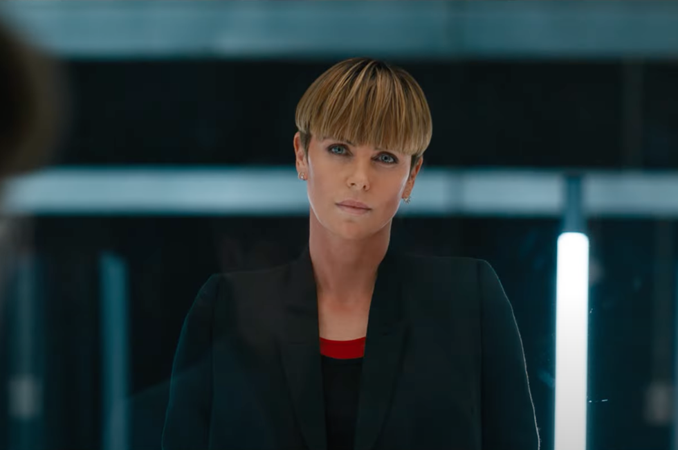 charlize theron stands in the middle of the frame with a straight face in fast and furious trailer