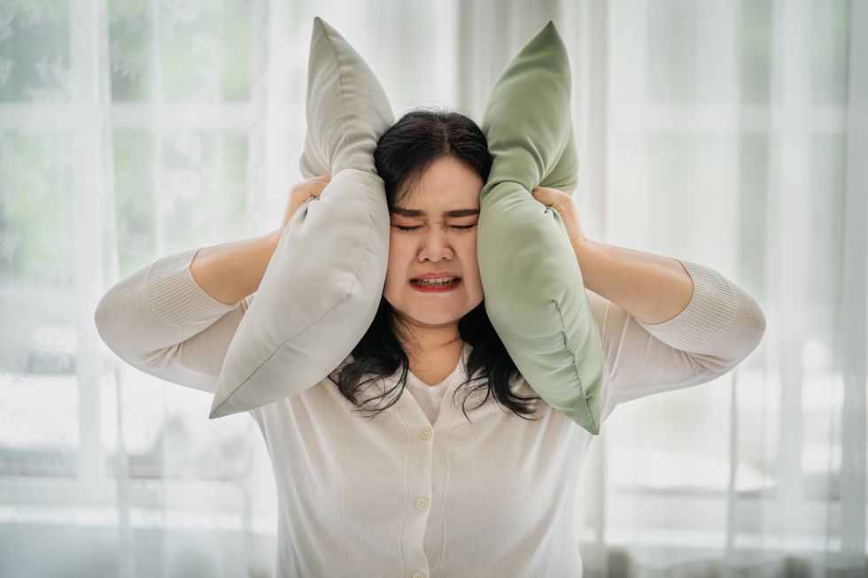 fat woman covering her ears with a pillow the concept does not want to hear things affecting oneself