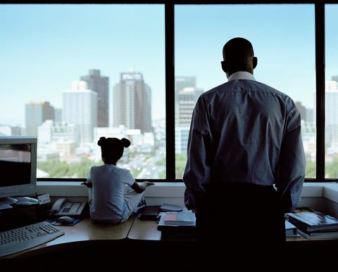 father and daughter looking out office window, rear view