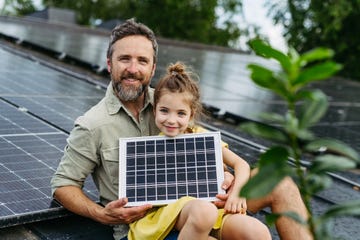 un padre y una hija en un techo con placas solares