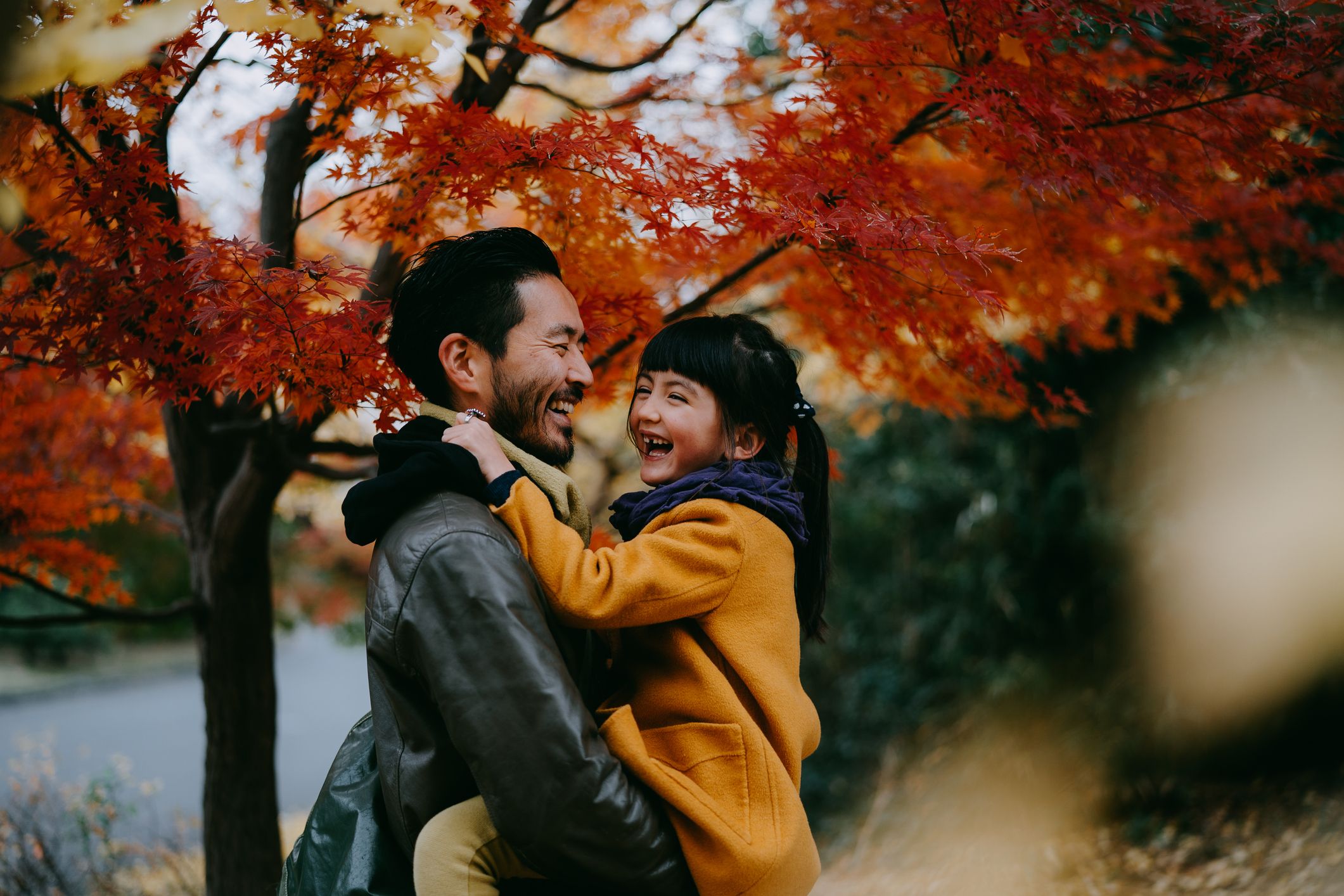 father and daughter standing under fall tree