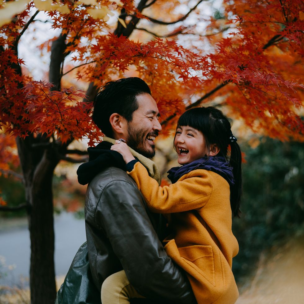 father holding cute little girl and laughing together under red japanese maple leaves, tokyo, japan
