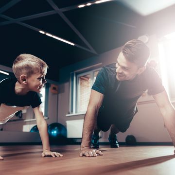 Father And Son Are Doing Push Ups In The Gym.