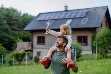 padre con su hijo en hombros en una casa de campo con paneles solares