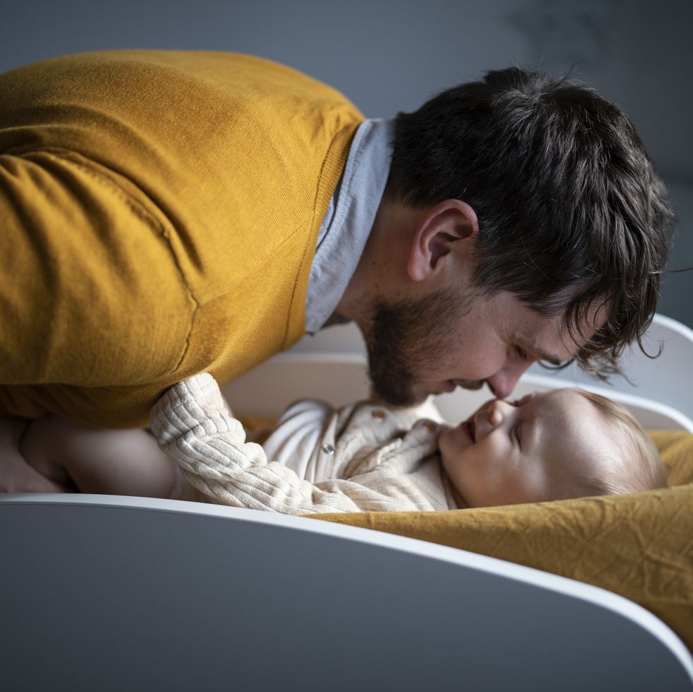 father changing clothes and diapers to his baby boy at home.