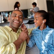 portrait of a happy father and daughter listening to music with headphones on a tablet computer and smiling   lifestyle concepts