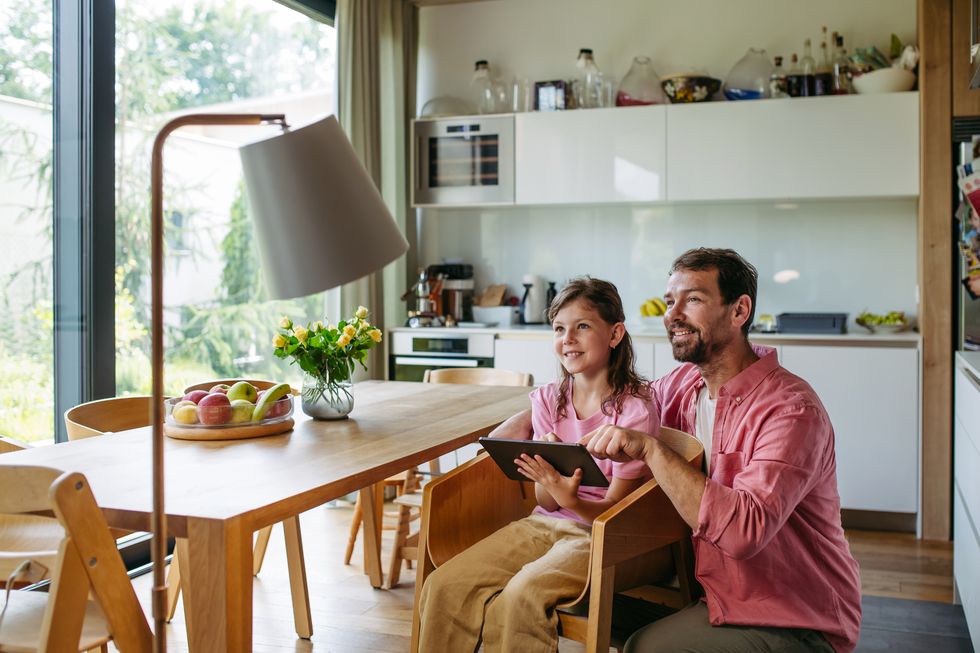 padre e hija en un salon de una casa con una tablet