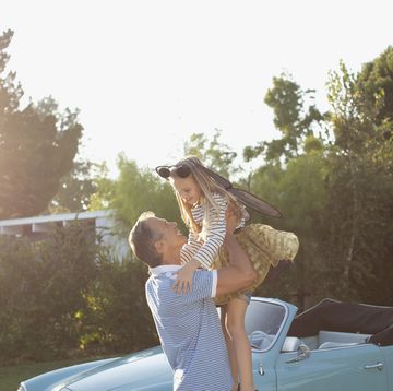 father lifting daughter in air outdoors