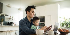 father multi tasking with young son 2 yrs at kitchen table