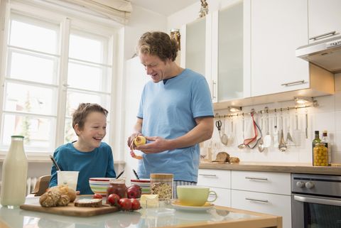 father peeling apple for son at breakfast table