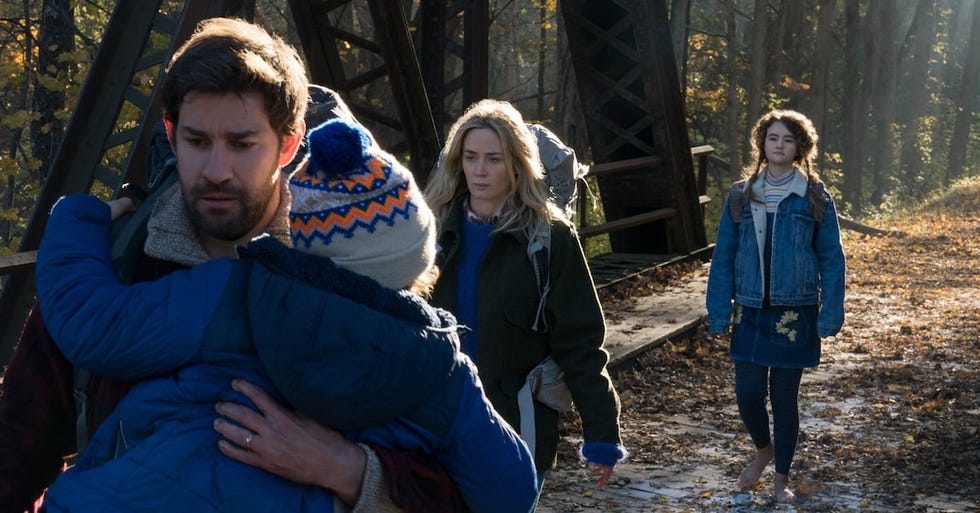 a family walks silently in a scene from a quiet place