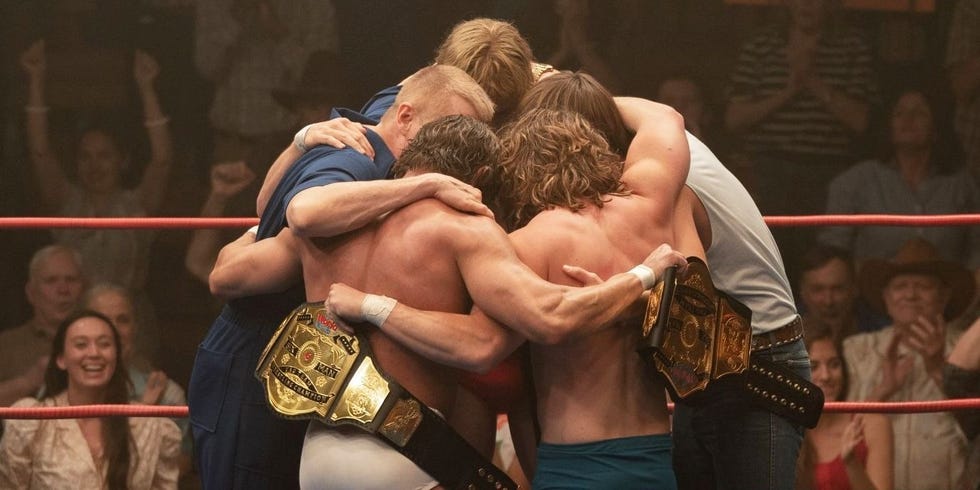 the von erich family huddles in a the ring in a scene from the iron claw