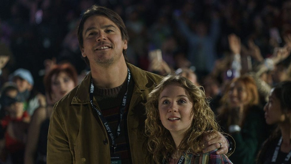 a father puts his arm around his daughter at a concert in a scene from trap
