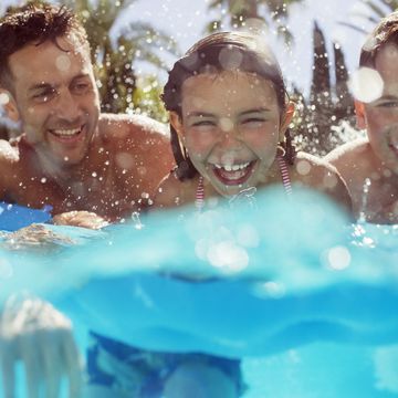 father swimming with his two children in swimming pool