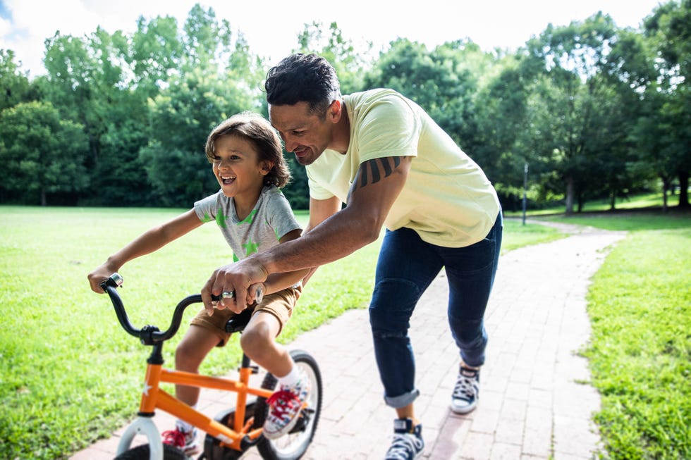 padre enseñando a montar en bici a su hijo