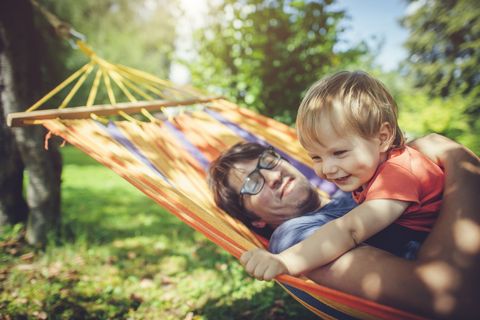 father and young child enjoying summer day in hammock