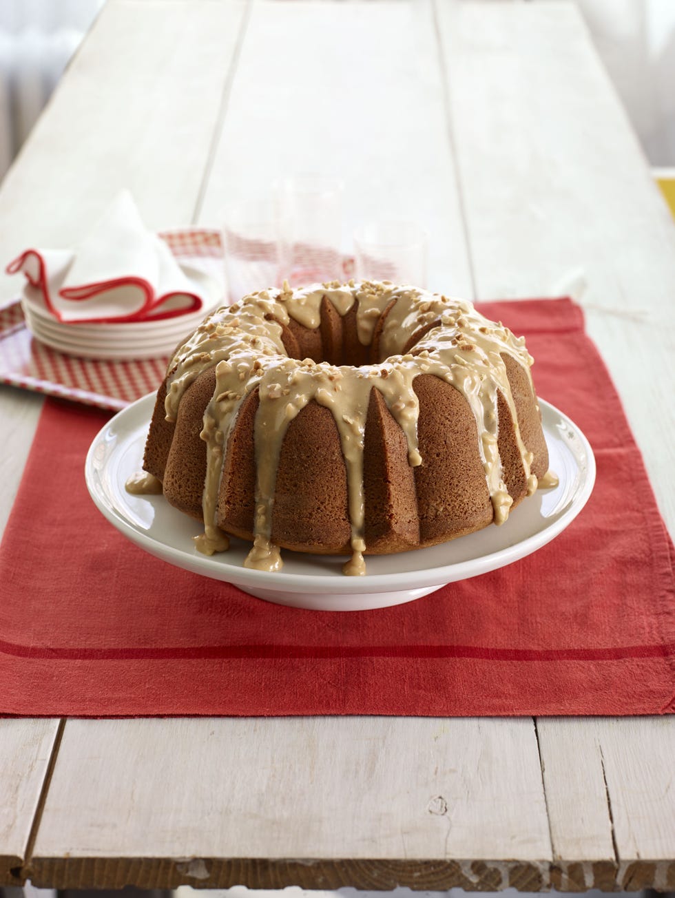 peanut butter bundt cake with peanut butter drizzled on a white cake stand