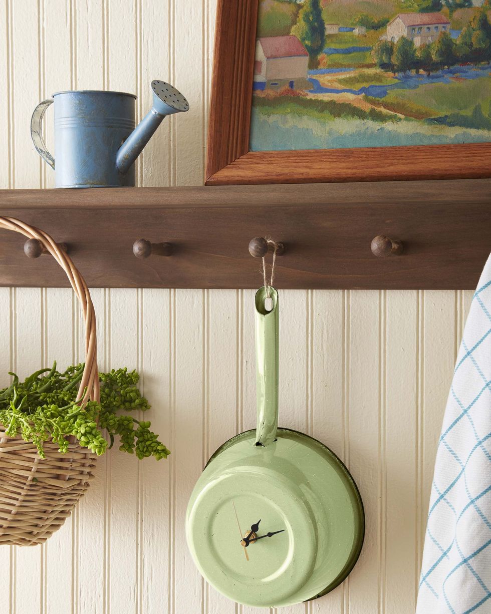father's day craft featuring a pale green enamelware pot turned into a clock, shown hanging by its handle from a wooden display shelf and rack