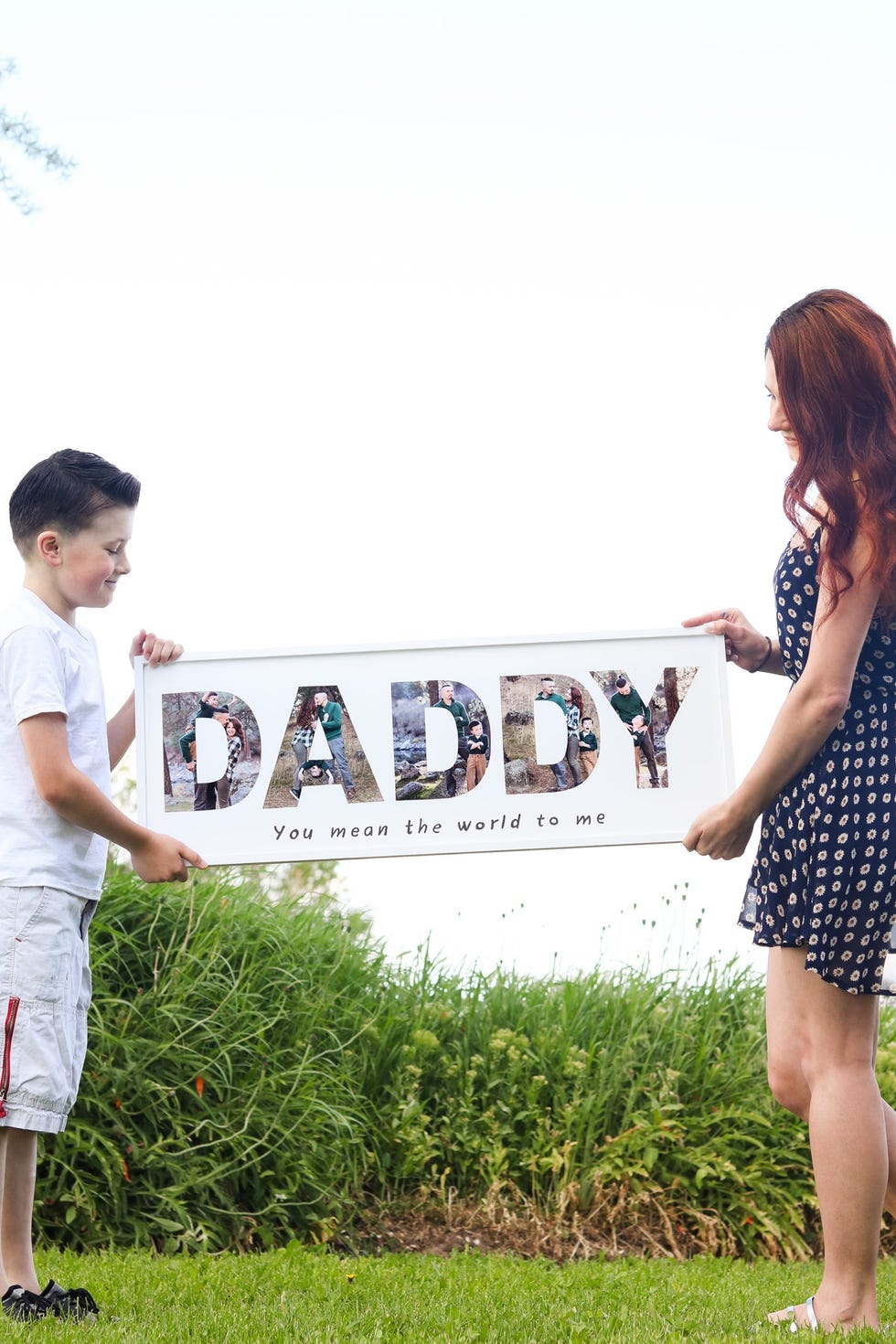 two kids hold up a frame that says daddy in photos