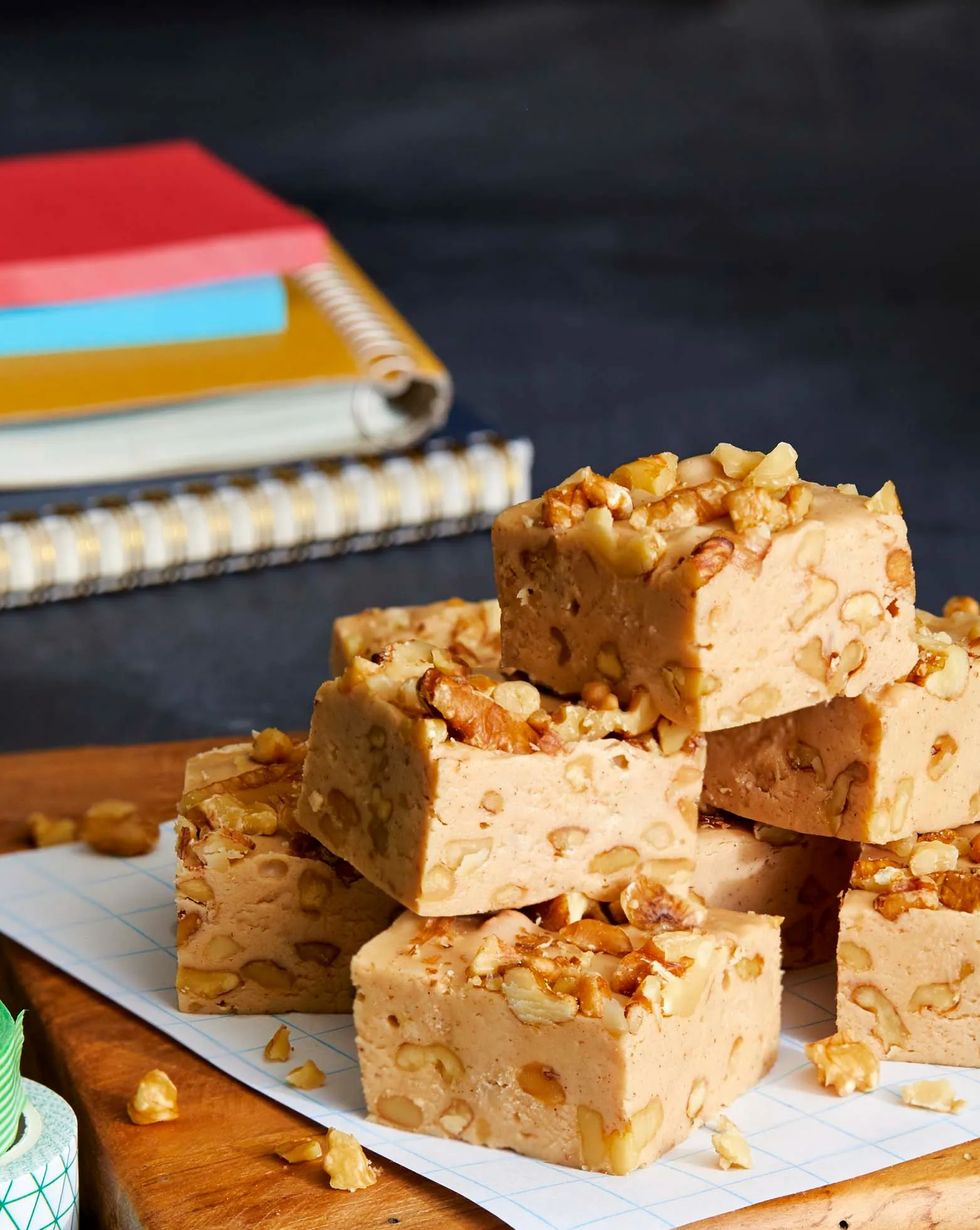 squares of maple cinnamon and walnut fudge stacked on a wooden serving board