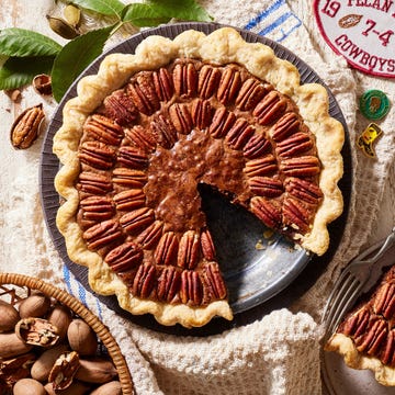 pecan brownie pie in a metal pie plate with a basket of pecans