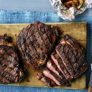 grilled rib eyes on wood board with blue linen and foil packet