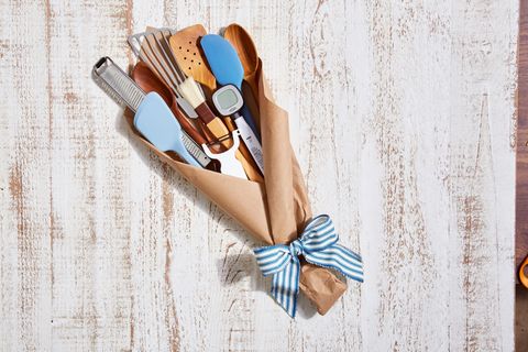 kitchen spatulas, thermometer, and microplane grater wrapped in brown craft paper and tied with blue and white stripe ribbon to resemble a bouquet for a fathers day gift basket