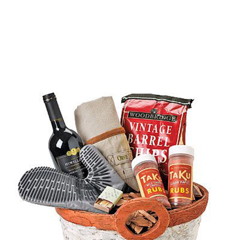 bark covered basket filled with silicone bbq mitt, bbq runs, leather apron, wine, matches, and wood chips